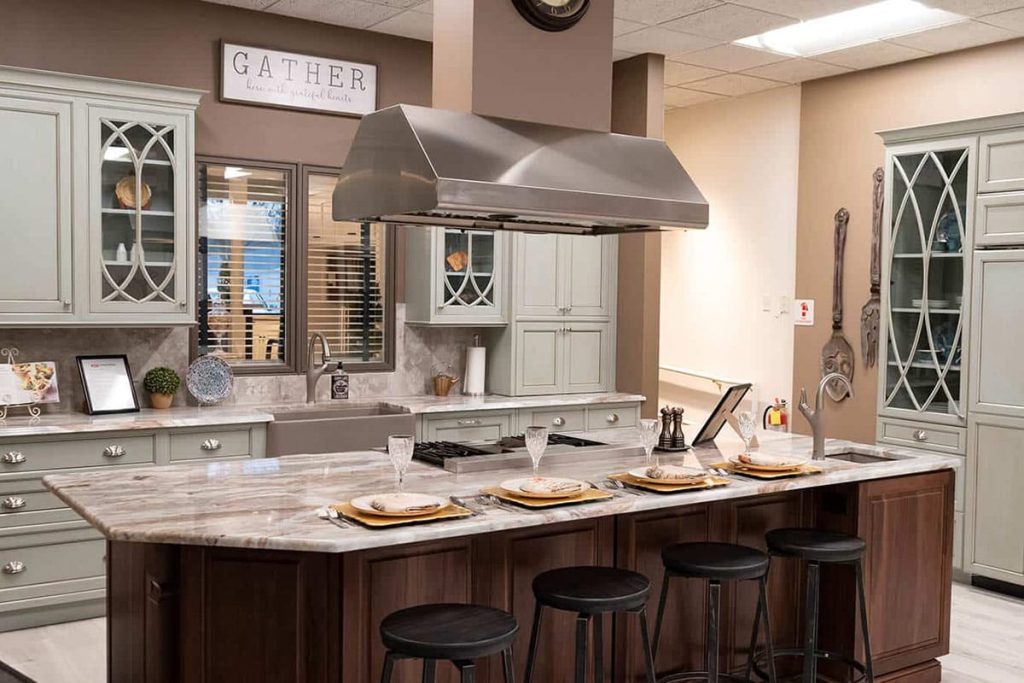 Modern kitchen design featuring gray cabinetry, marble countertops, and a central island with bar stools, showcasing a stylish and functional space for home renovations at Dartmouth Building Supply's Design Center.