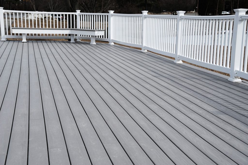 Gray composite decking with white railing and bench, ideal for outdoor renovations and summer entertaining.